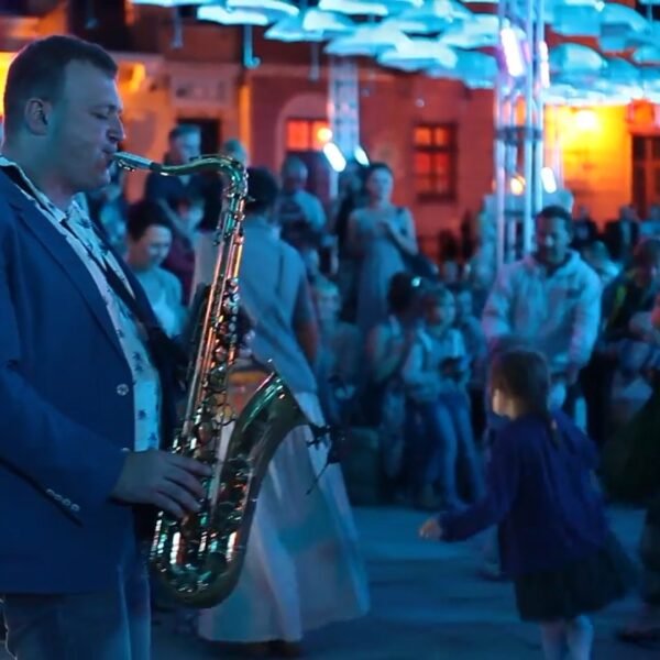Michał Borowski grający na saksofonie podczas plenerowego wydarzenia z publicznością